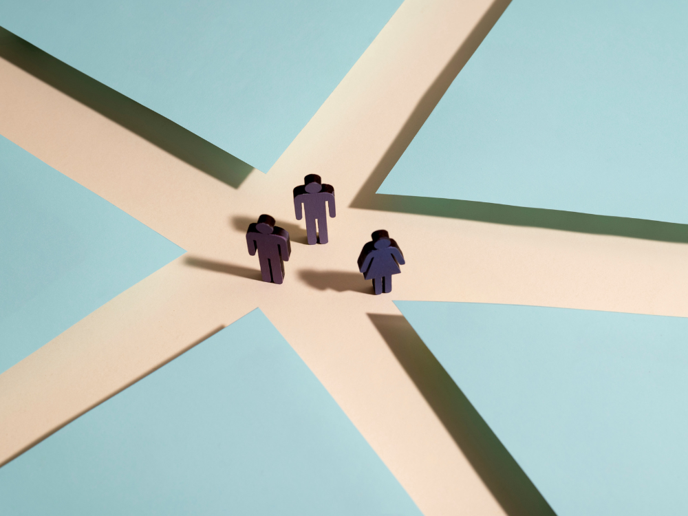 Three purple figurines stand where tan intersecting lanes meet on a light blue background.